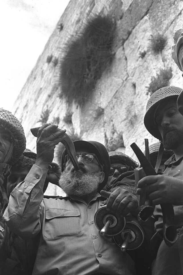 Rabbi Shlomo Goren blowing the shofar at the Western Wall surrounded by IDF soldiers, June 1967